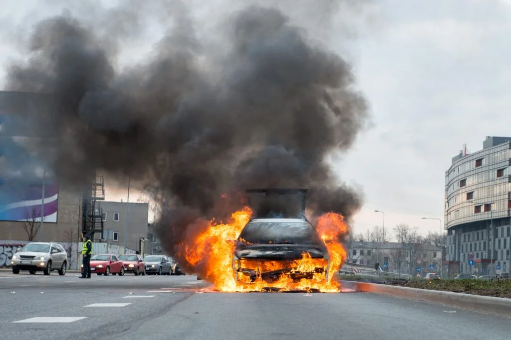 A few minutes in the street burnt car. Traffic is stopped. Firef