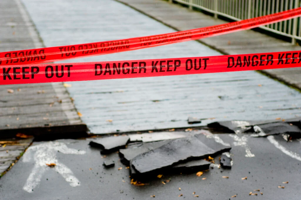 Red tape reading 'danger keep out' preventing people crossing a bridge.