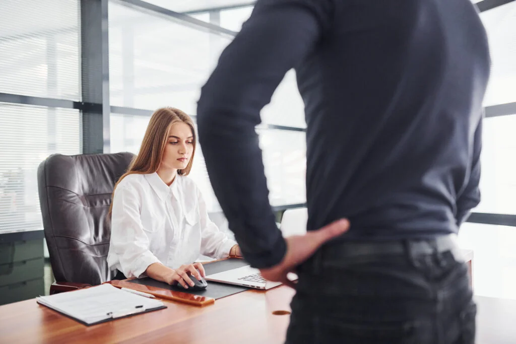 Rear view. Woman and man in formal clothes working together indoors in the office by table